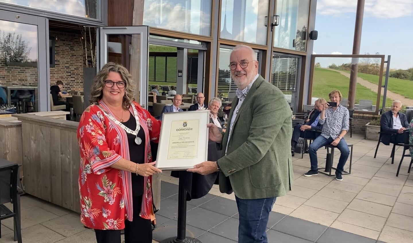 Wethouder Marjolein Steffens overhandigt Paul Bronstring de gemeentelijke erespeld en de daarbij behorende oorkonde.