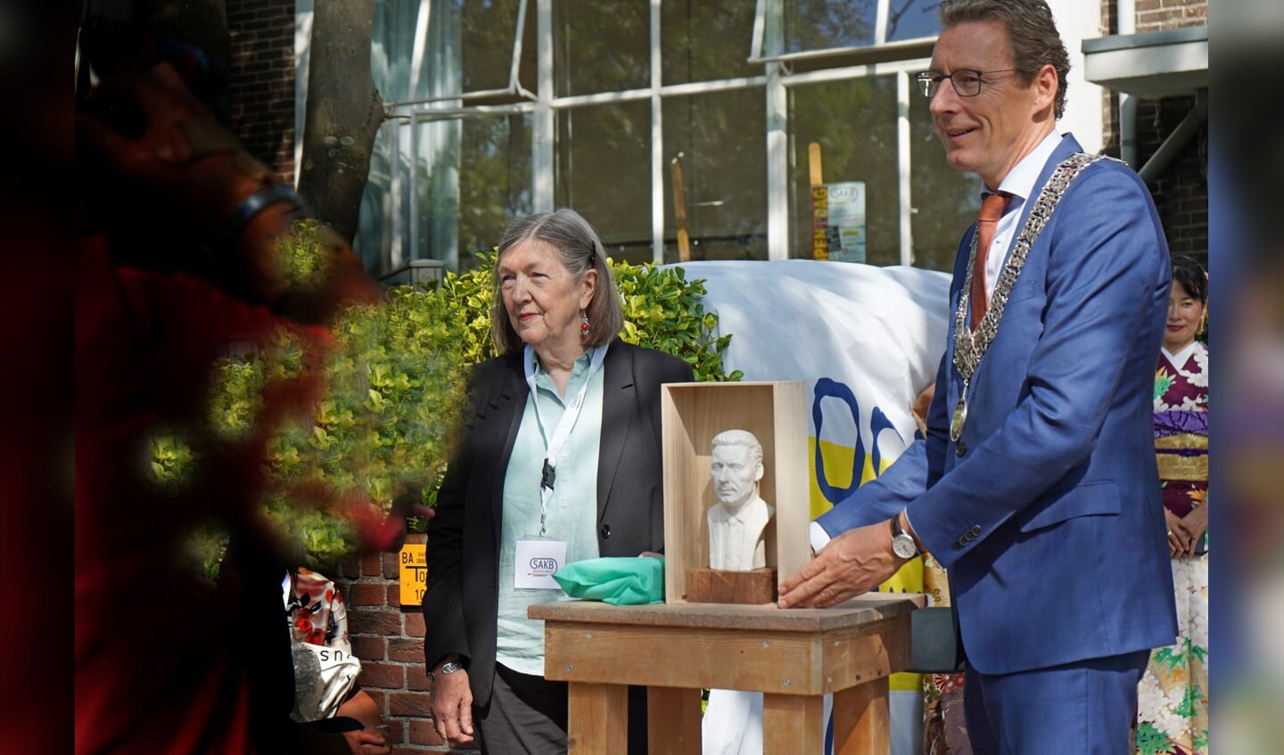 De burgemeester ontvangt het beeldje van Marian Sanders. 