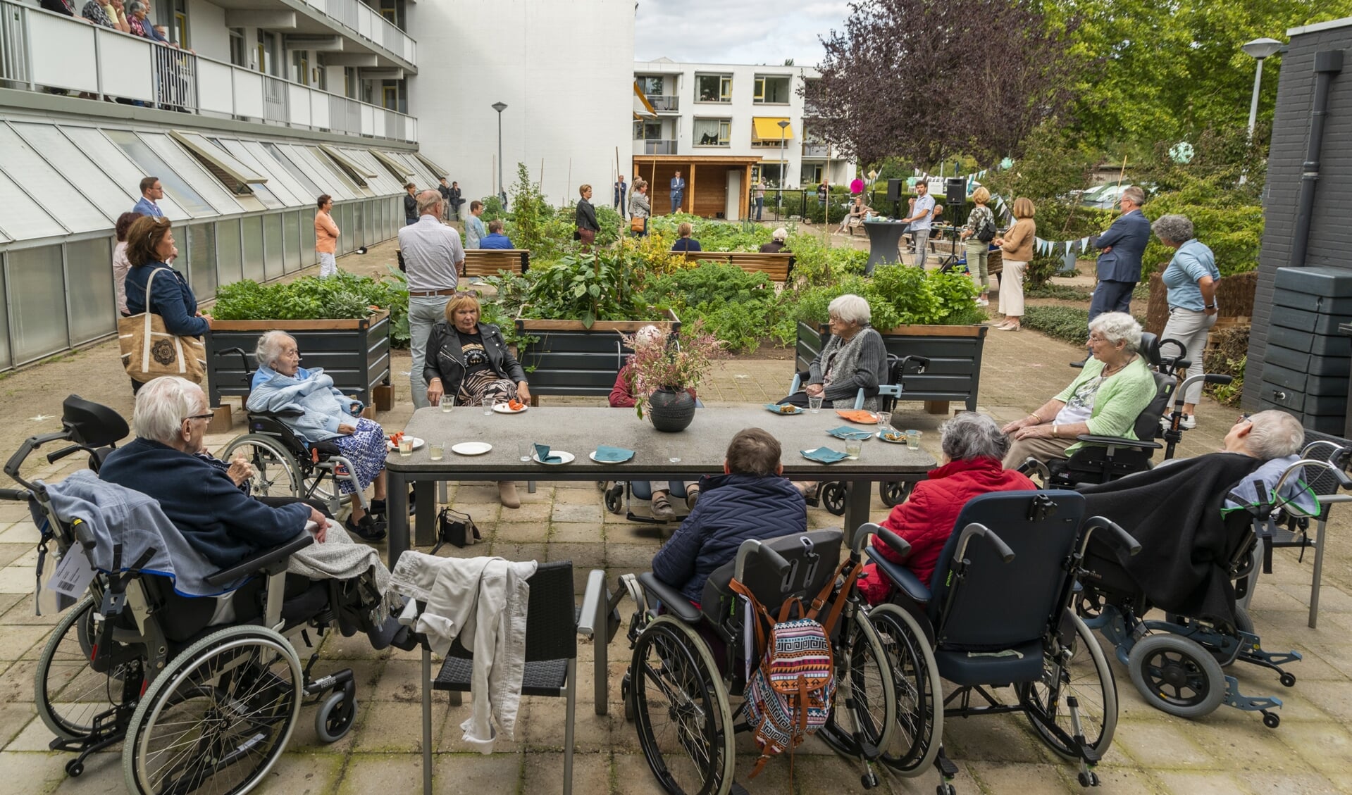 Bewoners van Ruimzicht en vrijwilligers van de buurtmoestuin vieren samen de officiële opening van deze tuin.