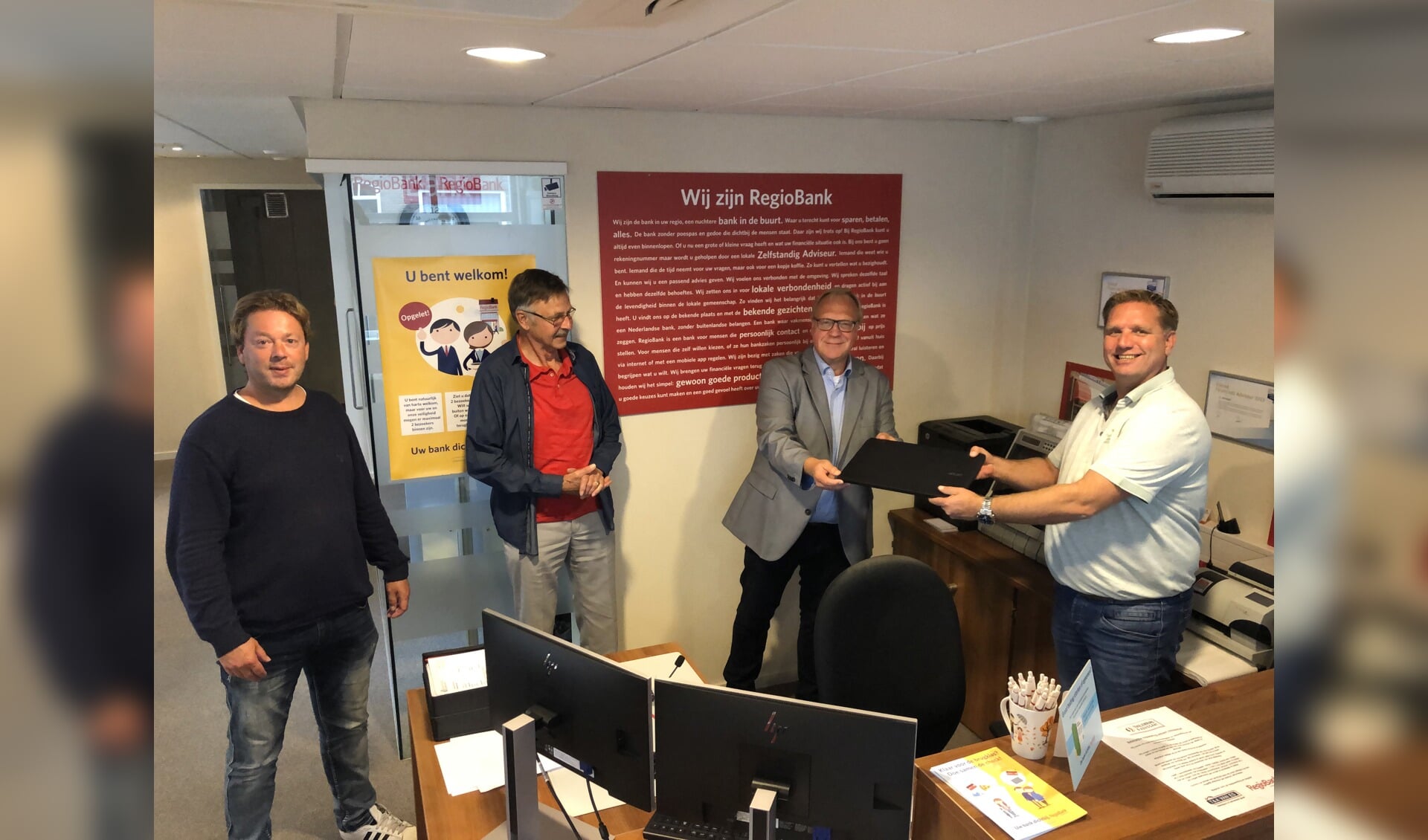 De overhandiging van de laptop, met Gerard Tekelenburg (Regiobank), Jacob van Vliet (voorzitter IDH), Henrie Pastoor (coördinator IDH) Andy Advocaat (Regiobank).