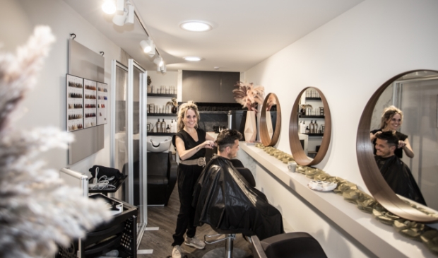 Marianne Minne - van Delen knipt Gerben Davelaar, haar eerste klant in de nieuwe salon.