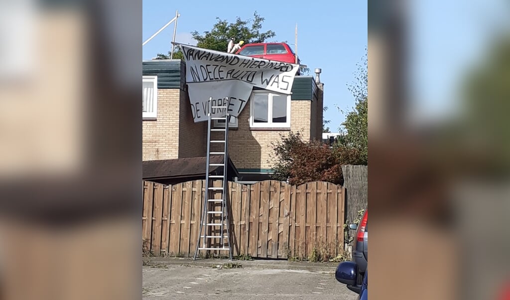 Een auto bovenop het dak, met een veelzeggende tekst.