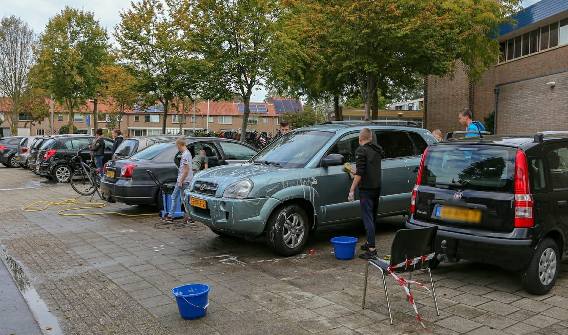 Tieners druk in de weer met auto's wassen.