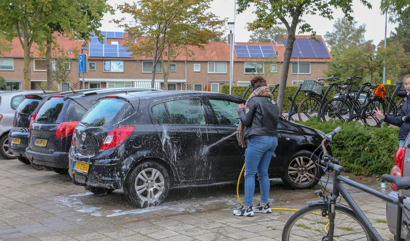 Tieners druk in de weer met auto's wassen.