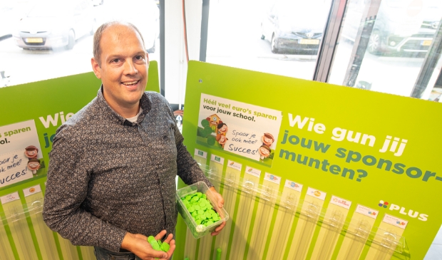 <p>Elbert van den Doel bij de wand met ‘spaarbuizen’ in zijn supermarkt.</p>