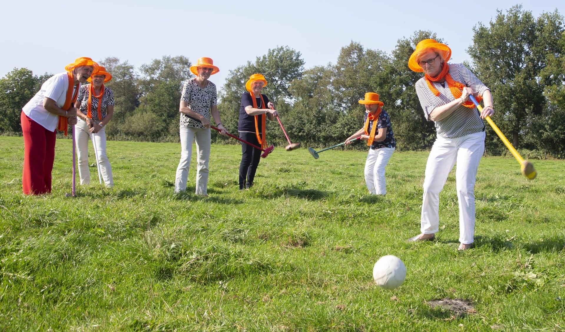 Mien Harthoorn slaat tijdens hun alternatieve Prinsjedagviering af voor een potje boerengolf. De andere 'Oranje meisjes' kijken toe.