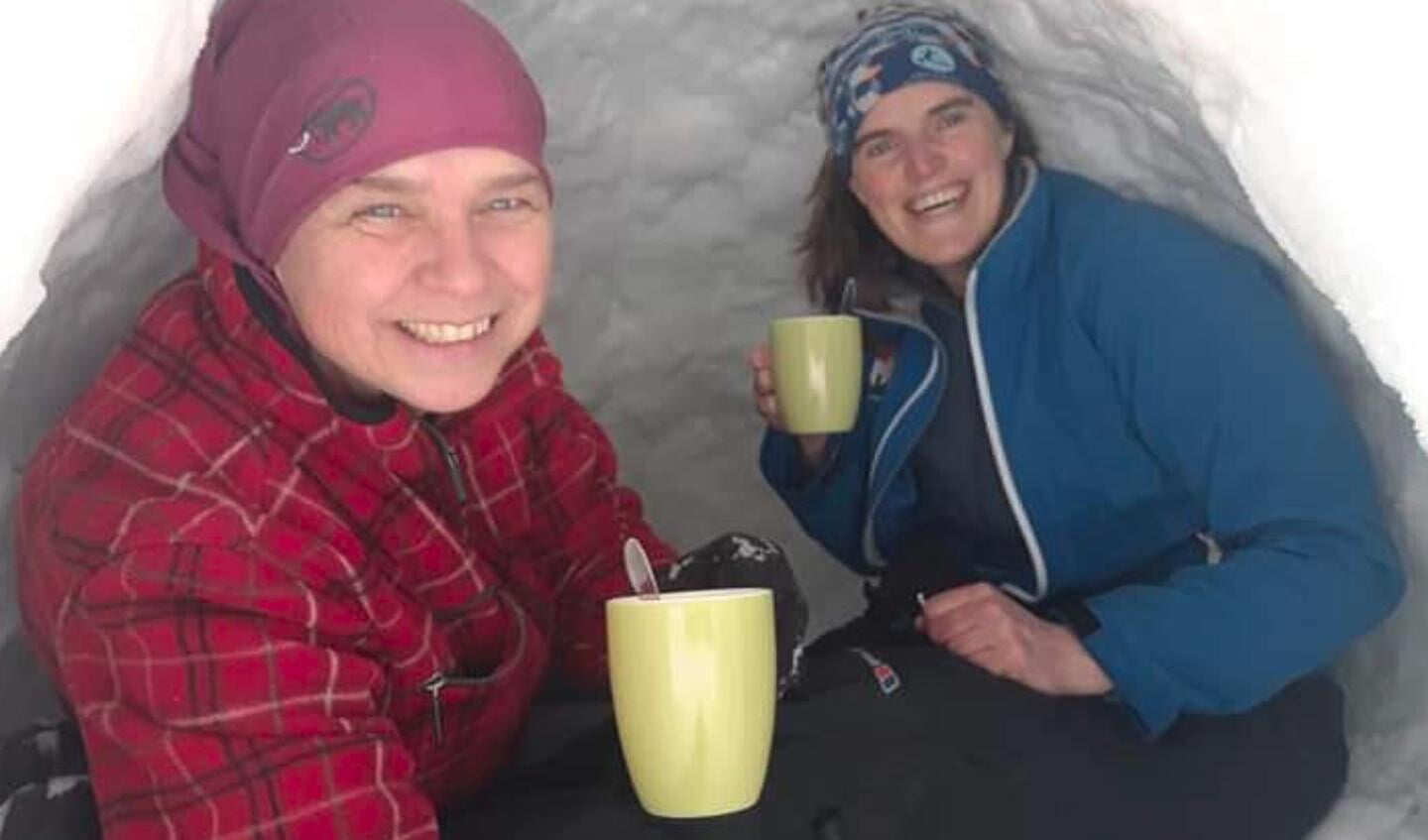 Petra en Esther Hoolwerf genieten van een beker warme chocomelk in hun zelfgemaakte iglo.