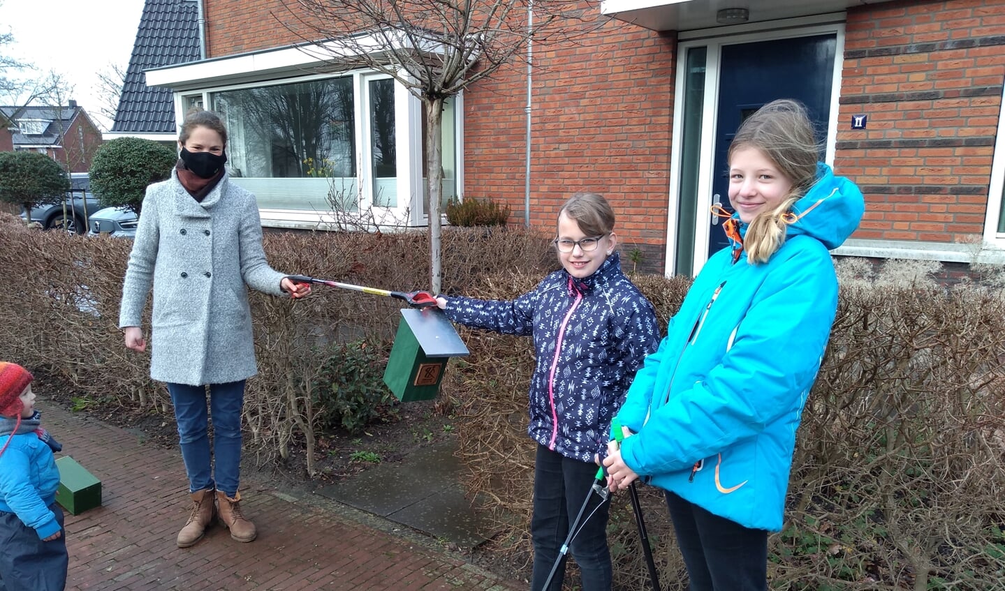 Auke Otto overhandigt de vogelhuisjes aan Merel en Hanna.