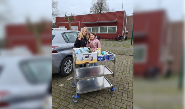 Febe en Gwen met producten voor de voedselbank.