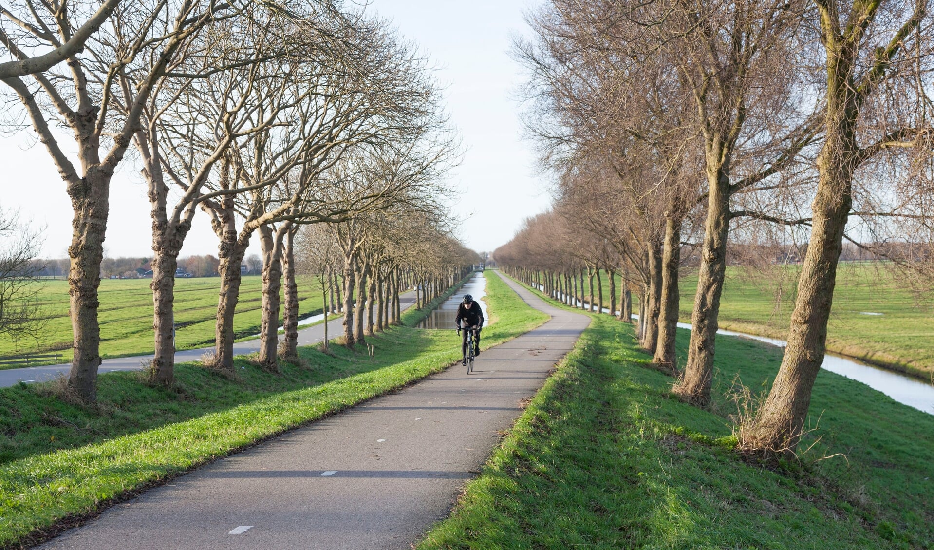 Fietser klimt dijk van de polder Purmer ten noorden van Amsterdam in Nederland op fietspad