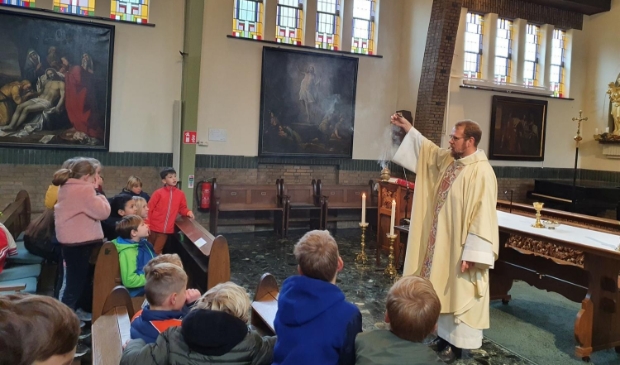 <p>Pastoor Runhaar, die deze zomer naar Utrecht verhuist, laat een Amersfoortse schoolklas zien hoe in de kerk wierook wordt gebruikt.</p>