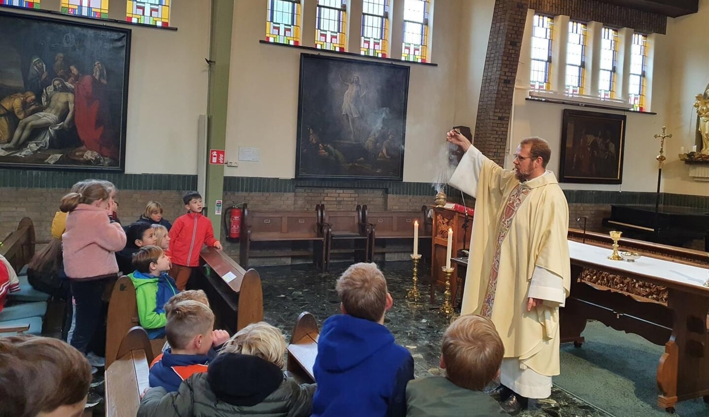 Pastoor Runhaar, die deze zomer naar Utrecht verhuist, laat een Amersfoortse schoolklas zien hoe in de kerk wierook wordt gebruikt.