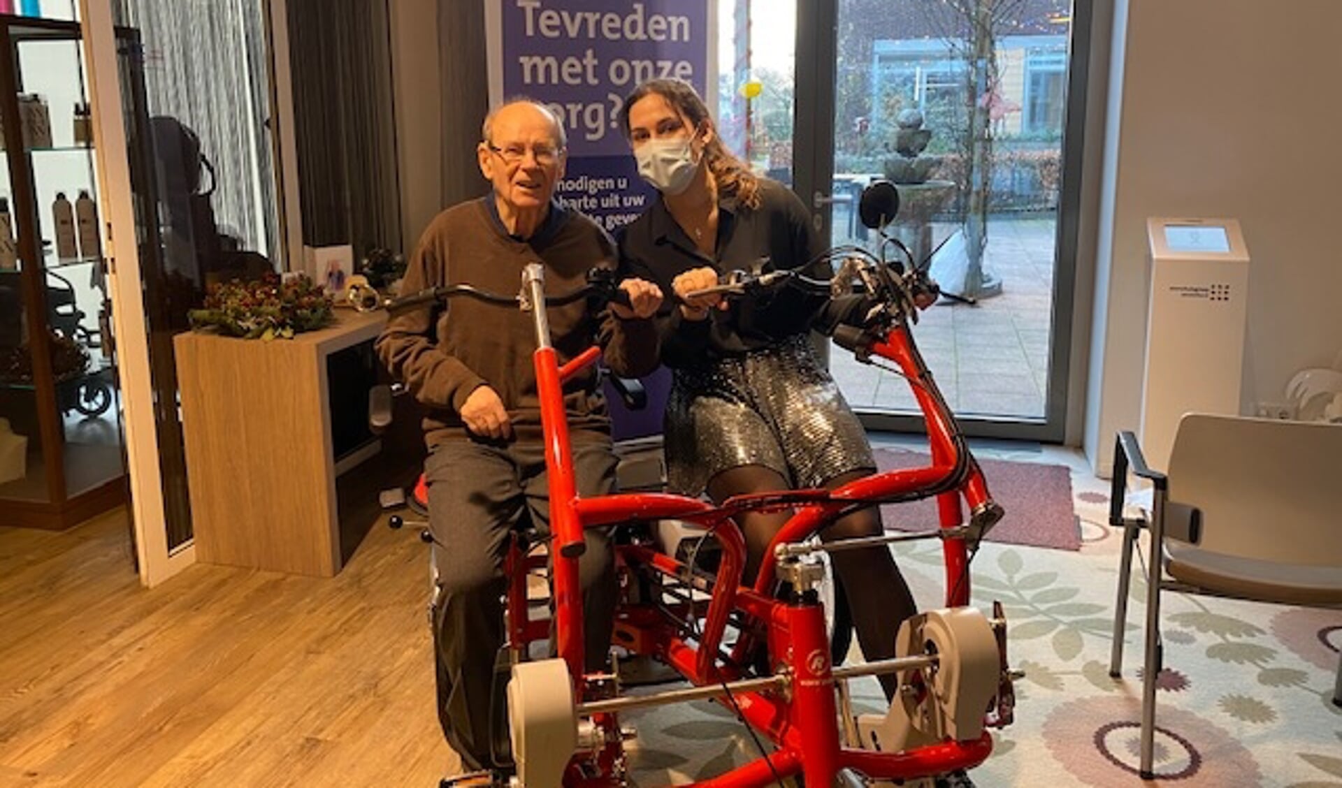 Kelley probeert samen met bewoner meneer Schippers de nieuwe fiets uit.