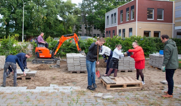 Kinderen, vrijwilligers en personeel werken samen aan de voorbereidingen voor de Schou-tenhoeve. Ton is actief op de kraan.