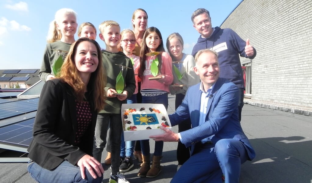 Juf Lenneke, de leerlingenraad, Gijs van de Laar, Hilde de Groot en Huib van Essen poseren voor de recent geplaatste zonnepanelen.