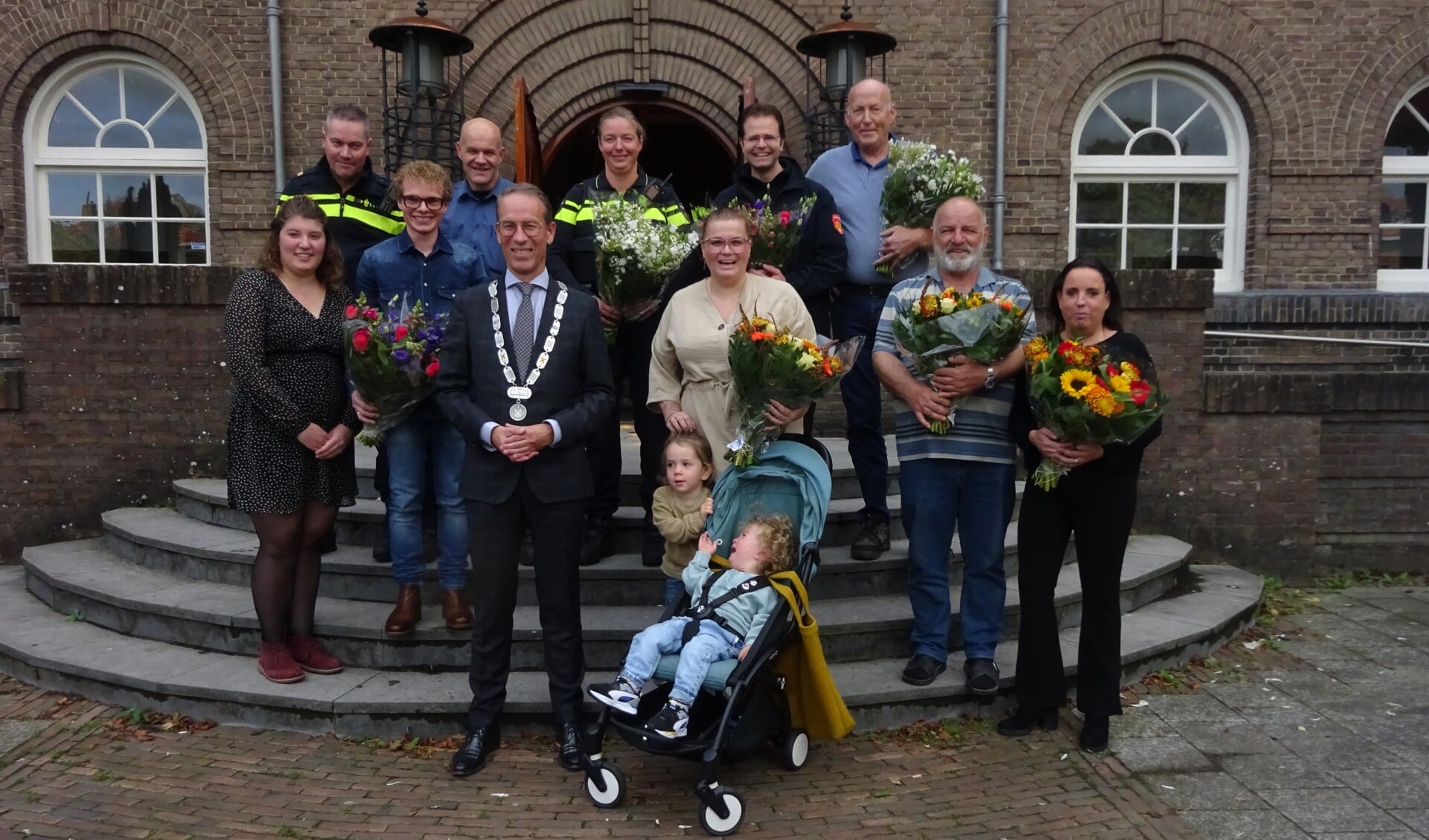 Roos Knoote (naast de burgemeester) met haar kinderen en de redders en hupverleners.