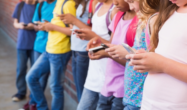 Cute pupils using mobile phone at the elementary school