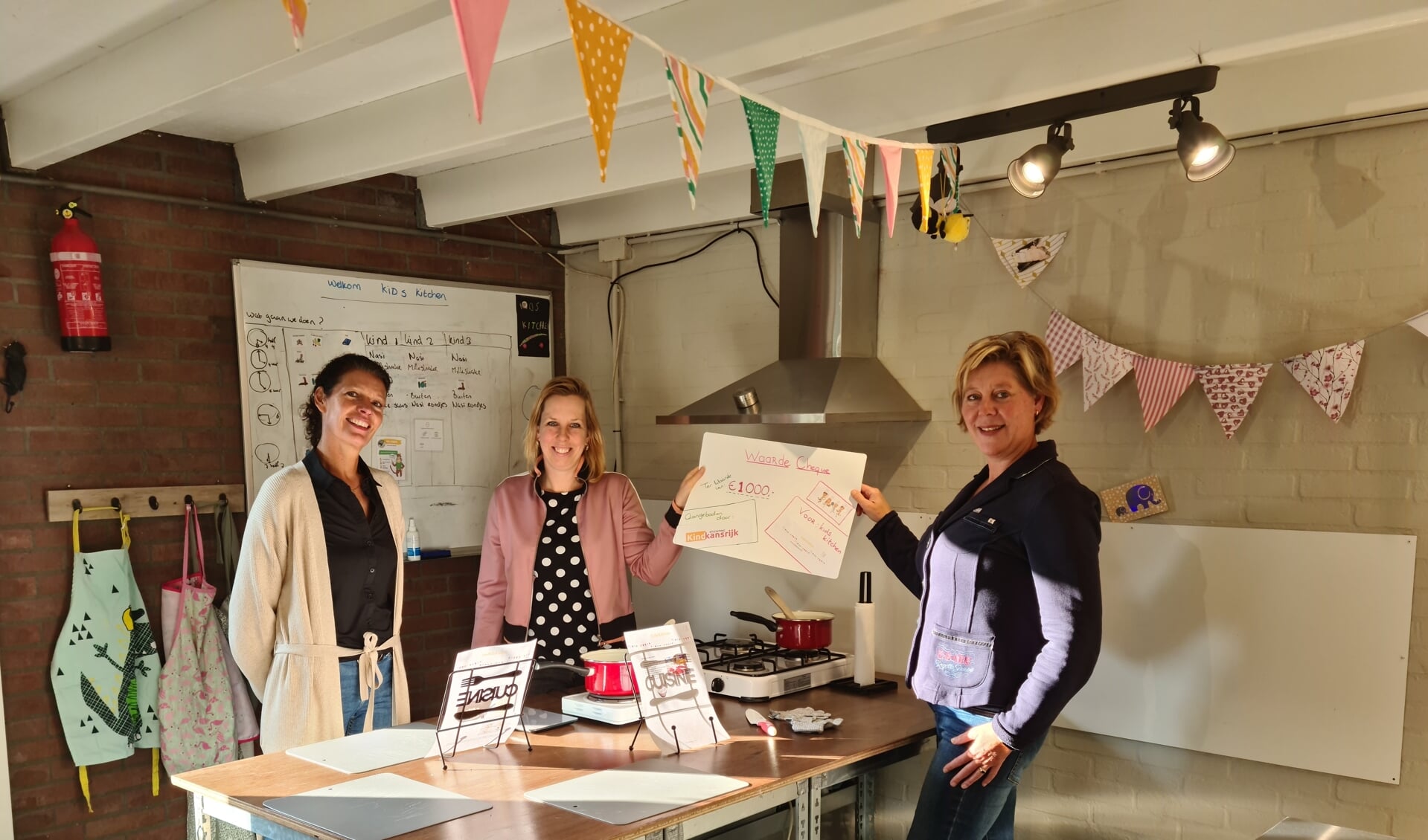 Marieke en Dorien van Stichting Kind Kansrijk overhandigen een cheque aan Bernadet van Kids Kitchen 
