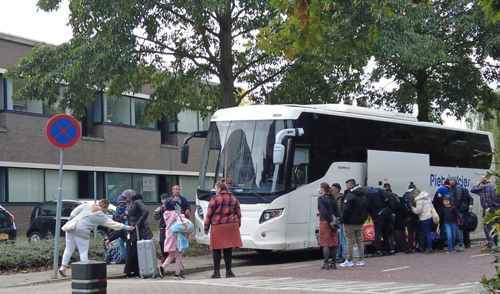 Bus met vluchtelingen voor noodopvang   in voormalig belastingkantoor