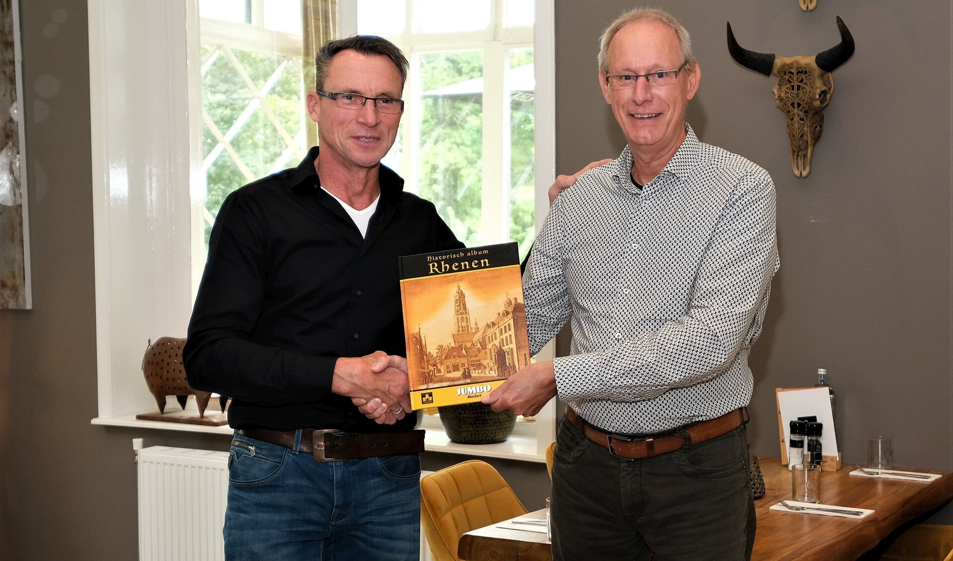 Cornelis Mostert ontvangt uit handen van Dries Huisman het eerste nog te plakken exemplaar het Historisch album Rhenen.