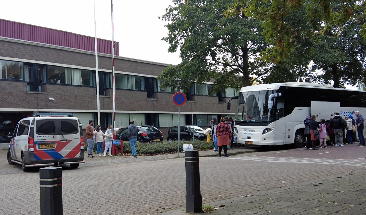 Bus met vluchtelingen voor noodopvang   in voormalig belastingkantoor