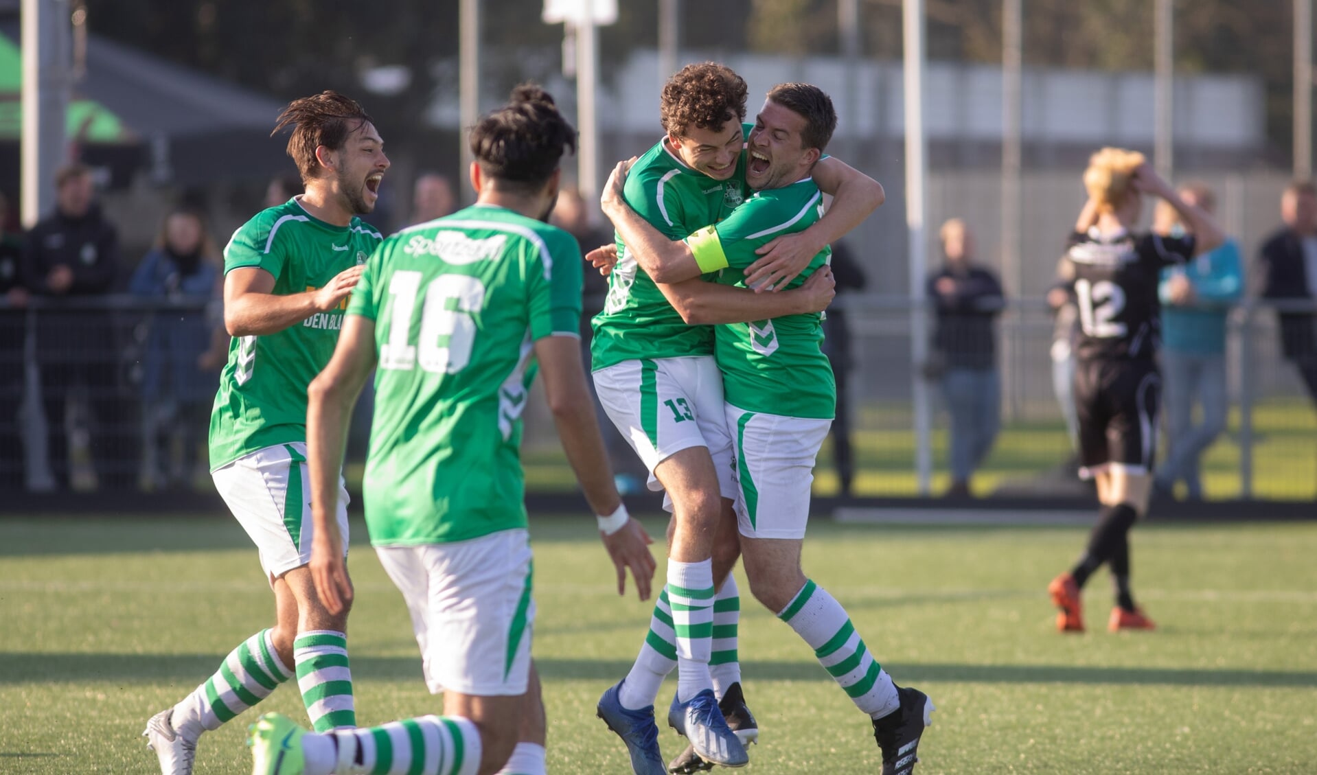 Invaller Joël van Waning heeft diep in blessuretijd de 4-4 gescoord en wordt geknuffeld door zijn teamgenoten.  