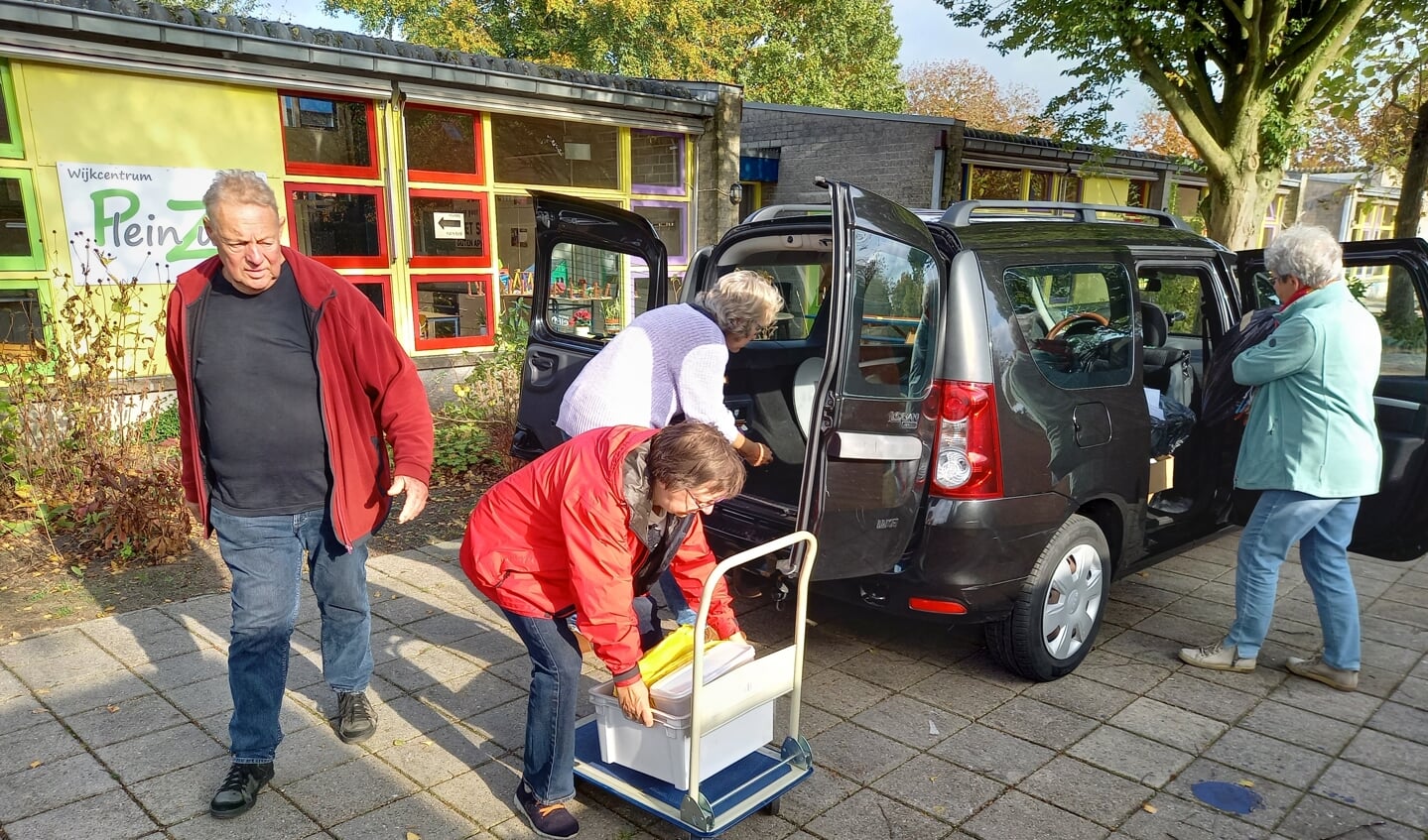 Bestuursleden bezig met het uitladen van de dozen bij wijkcentrum Plein Zuid.