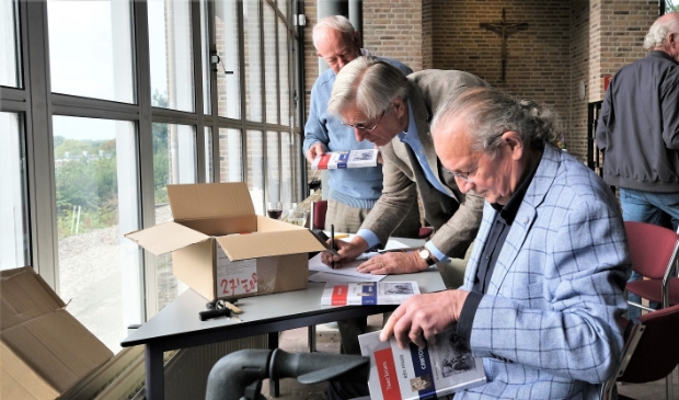 <p>Auteur Gerard van Loenen (r) bezig met het signeren van de boeken kort na de presentatie in de Gedachteniskerk in Rhenen. </p>
