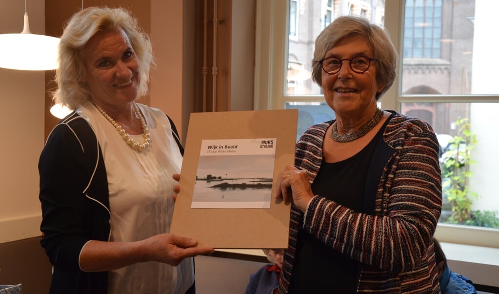 Janneke van Tilburg (Wijks Atelier) overhandigt symbolisch het eerste exemplaar van het boekje Wijk in Beeld dat binnenkort verschijnt