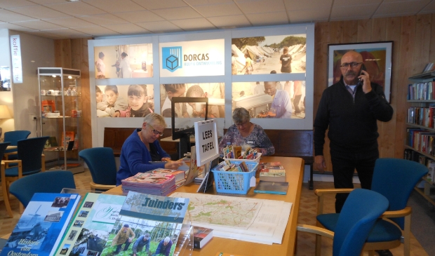 Jan van den Berg met twee van de vrijwilligers, die aan de leestafel boeken sorteren.