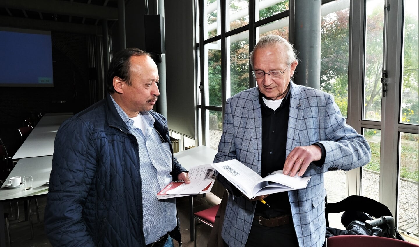 De schrijver bekijkt samen met Rijnpostredacteur Martin Brink de nieuwe publicatie. 