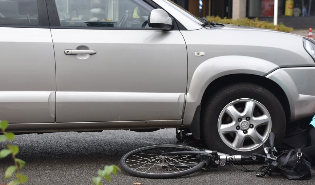 De fiets kwam klem te zitten onder een voorband van de auto.