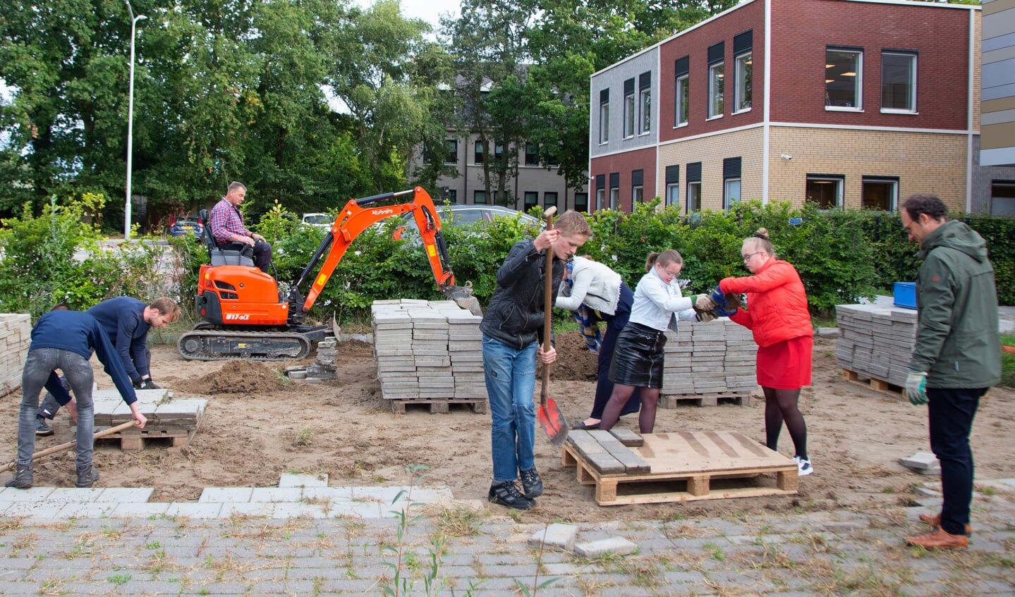 Kinderen, vrijwilligers en personeel werken samen aan de voorbereidingen voor de Schou-tenhoeve. Ton is actief op de kraan.