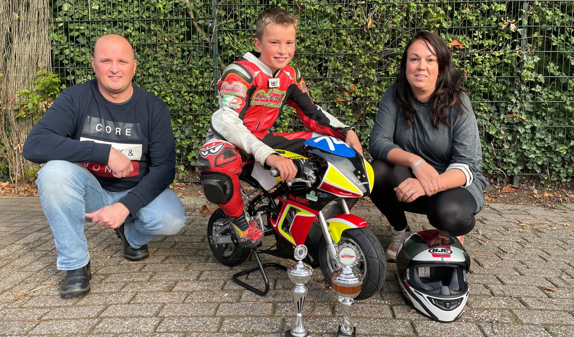 Mick Koomen op de minibike met zijn ouders Stefan en Daphne en de gewonnen bekers in het afgelopen jaar.