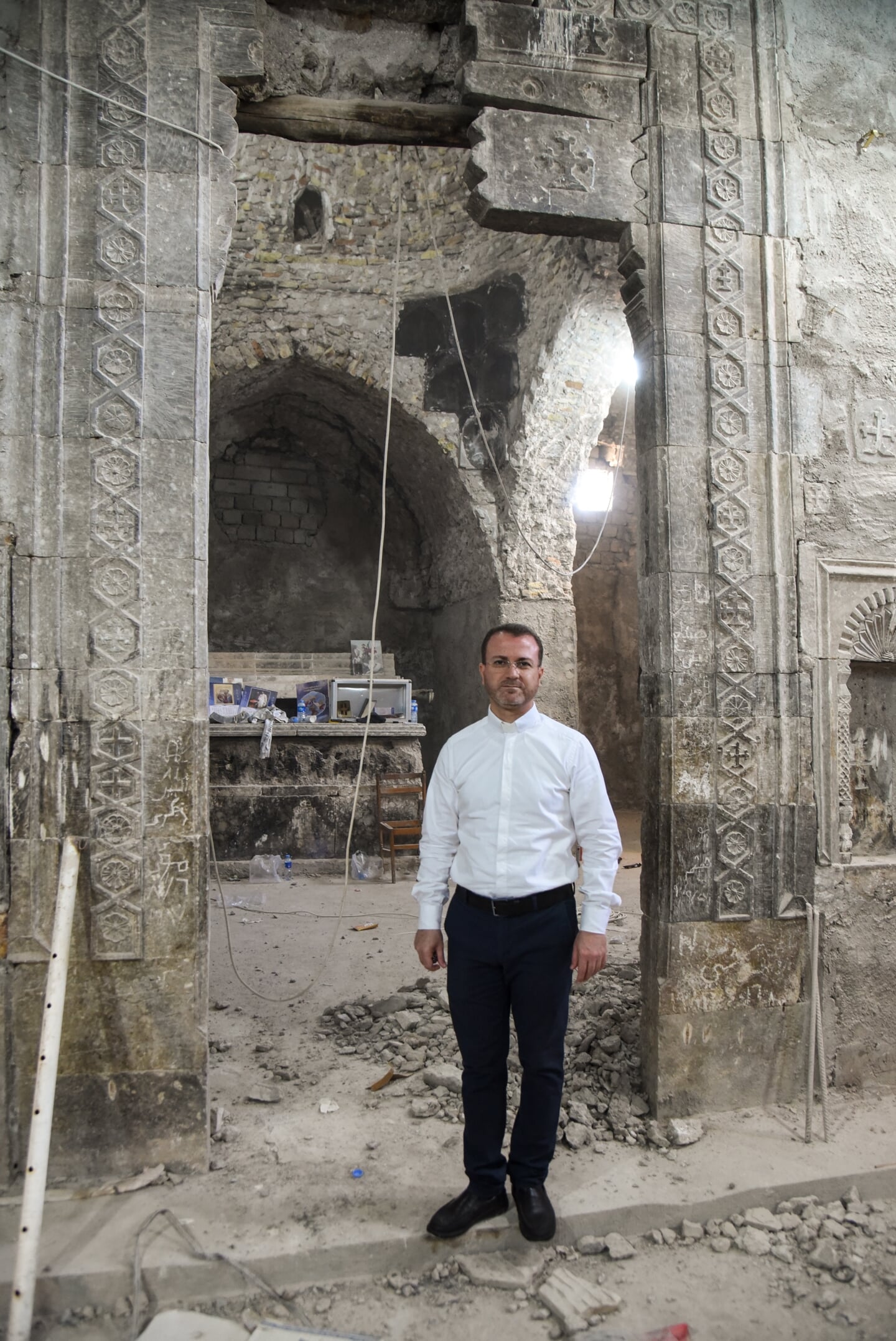 Priester Behnam Benoka in een verwoeste kerk Irak.
