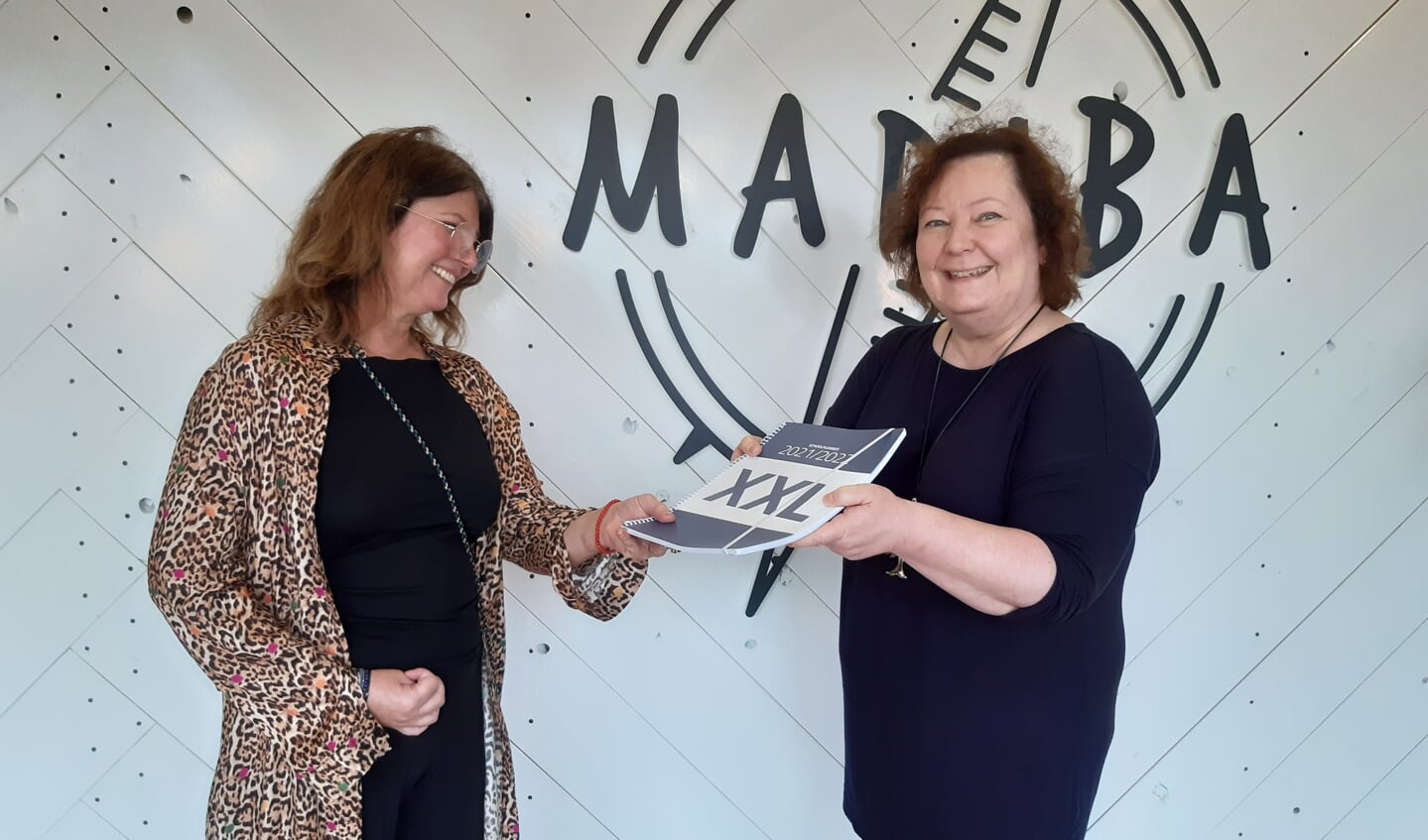 Mary Claassens van Projecthuis Madiba (links) ontvangt een schoolplanner uit handen van uitgeefster Ilse van der Stoep (rechts).