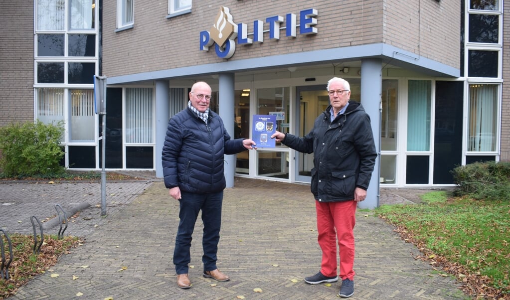 Henk Eggink (l) neemt het eerste exemplaar in ontvangst voor het huidige politiebureau op de hoek van de Eemnesserweg en Plataanlaan.