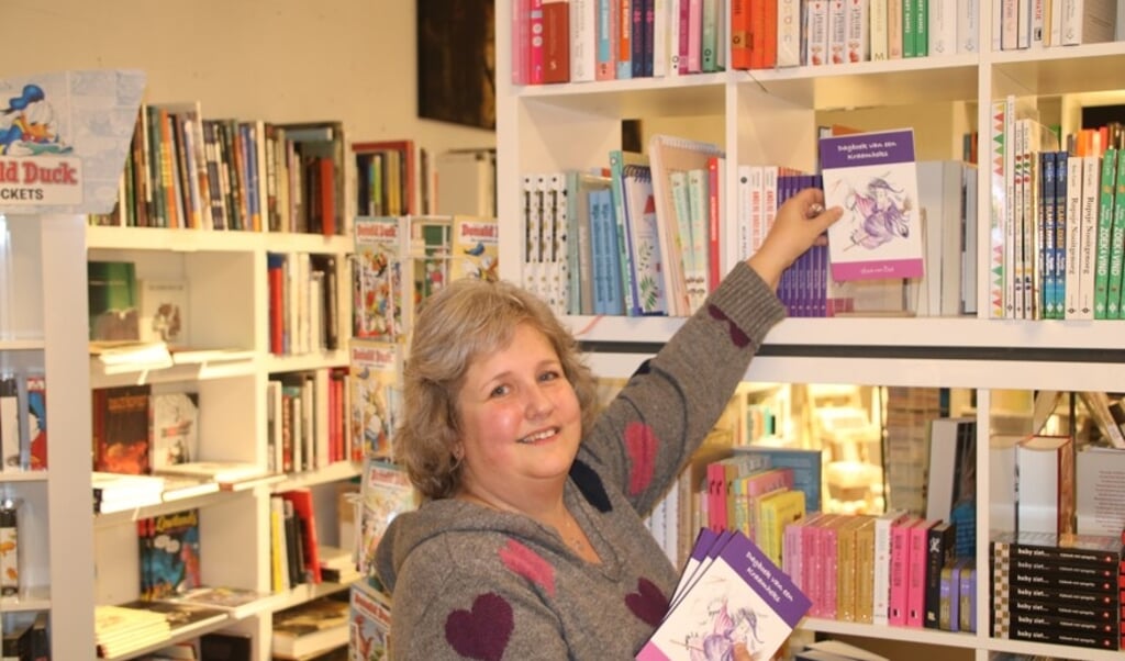 Emmy zet een paar van de exemplaren van ‘Dagboek van een Kraamheks in het schap bij boekhandel Stevens, waar het boek te koop is.   