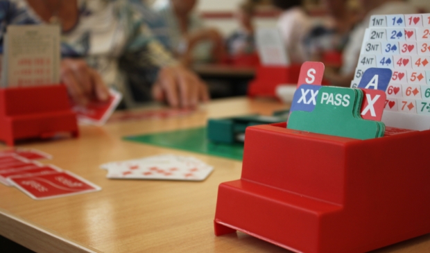Bridge is analytisch denken en gezellig een spel doen. Biedbakje op de bridgetafel.
