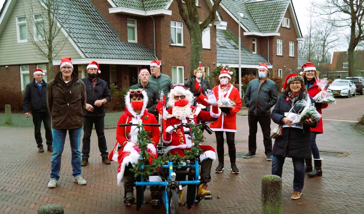 De vrijwilligers worden begeleid door de kerstman en kerstvrouw.