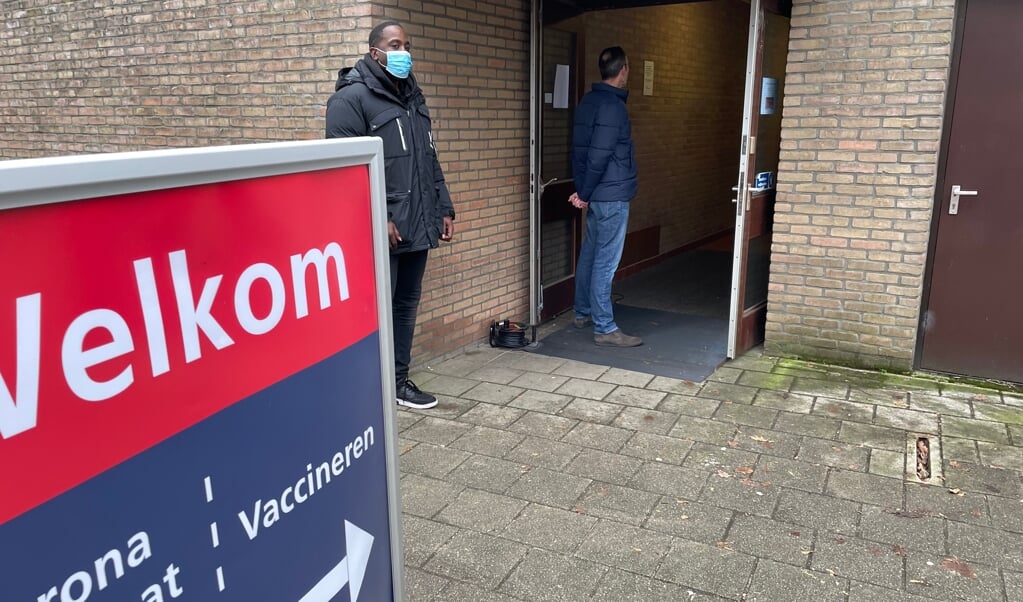Wachten in de rij voor een vaccinatie, met links een beveiliger, bij de ingang van 't Trefpunt in Voorthuizen.