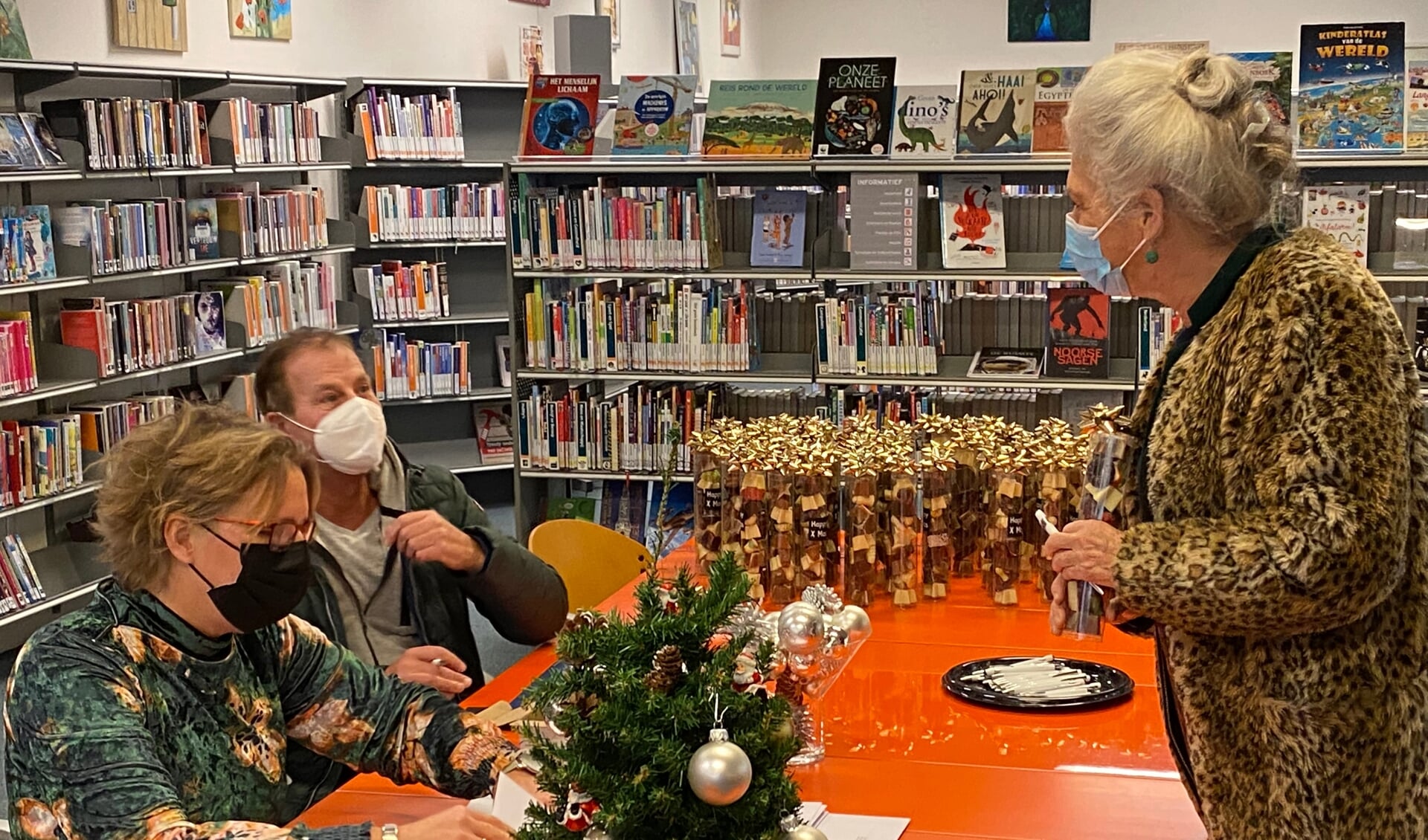 SWO-welzijnswerker Rianne van Ginkel en bestuurslid Henk Rijnders overhandigen een kerstattentie in de bibliotheek.