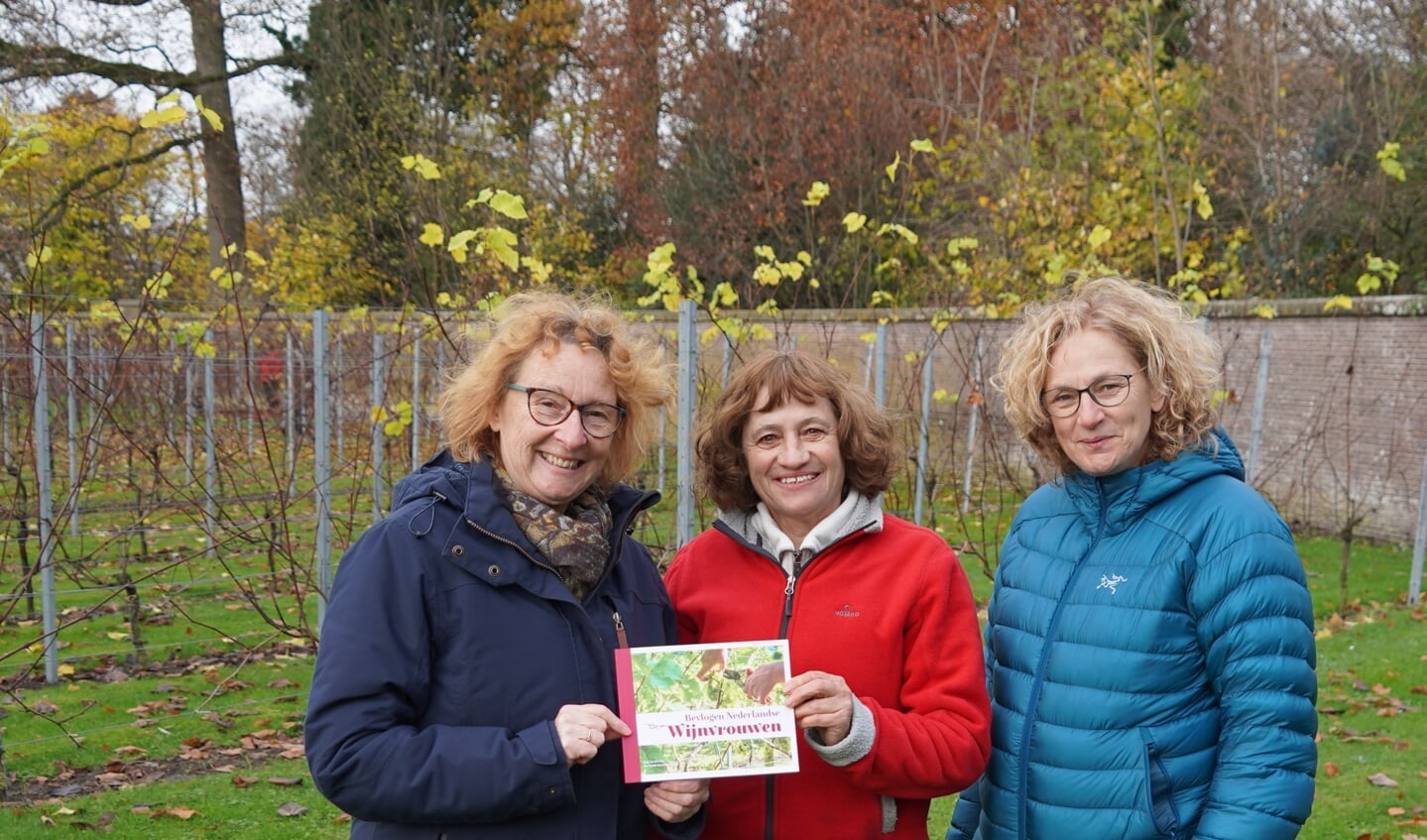 Joke van der Leij (links) en Ilse Swank (rechts) overhandigen het eerste exemplaar van hun boek aan Sigrid van Ede (midden).