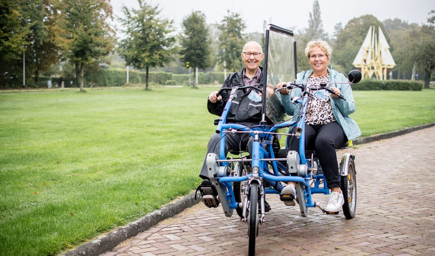 Gerard van Leeuwen en maatje Tekla Zwinkels op de duofiets. Het scherm dient als beveiliging tegen corona.