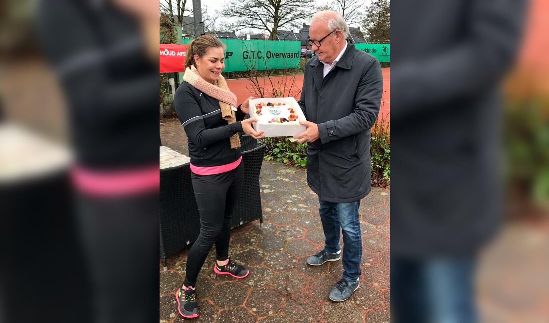 Nicky Steeman krijgt uit handen van voorzitter Hans Krielaart een taart met daarop haar inschrijvingsnummer 500.  