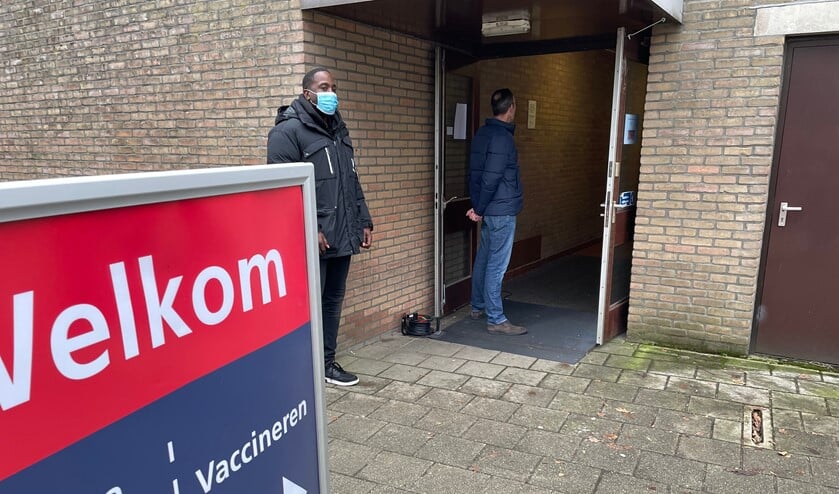 Wachten in de rij voor een vaccinatie, met links een beveiliger, bij de ingang van 't Trefpunt in Voorthuizen. 