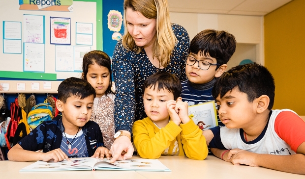 <p>Een juf leest met een aantal kinderen, die afkomstig zijn uit alle hoeken van de wereld. </p>