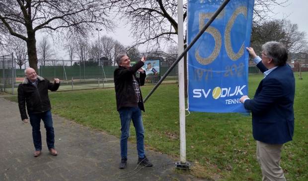 <p>Voorzitter Reinout van Elst hijst de jubileumvlag onder toeziend oog van Arnold Wagemakers (links) van het Sporthuis en wethouder Jocko Rensen.</p>