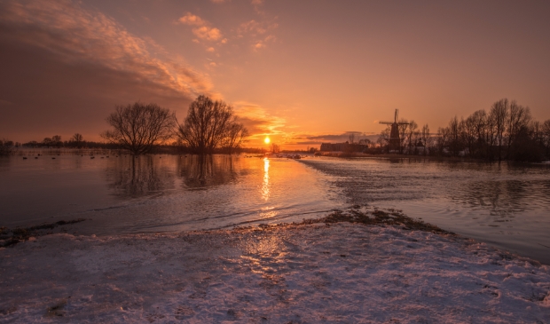 <p>Zonsondergang met sneeuw, ijs en een volstromende Woelse Waard met Gorinchem op de achtergrond</p>