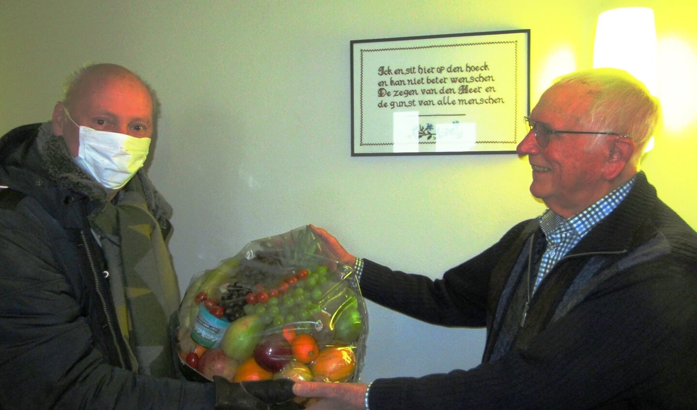Peter Bons, links op de foto, voorzitter van de Historische Vereniging Sliedrecht, biedt Jan van der Vlies een fruitmand aan.